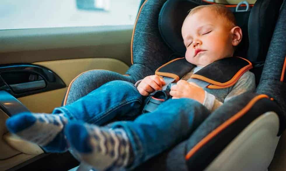 A baby boy fast asleep in his car seat
